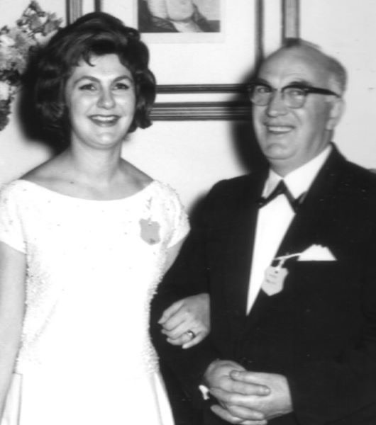 An older man in a suit with a young woman in a wedding dress
