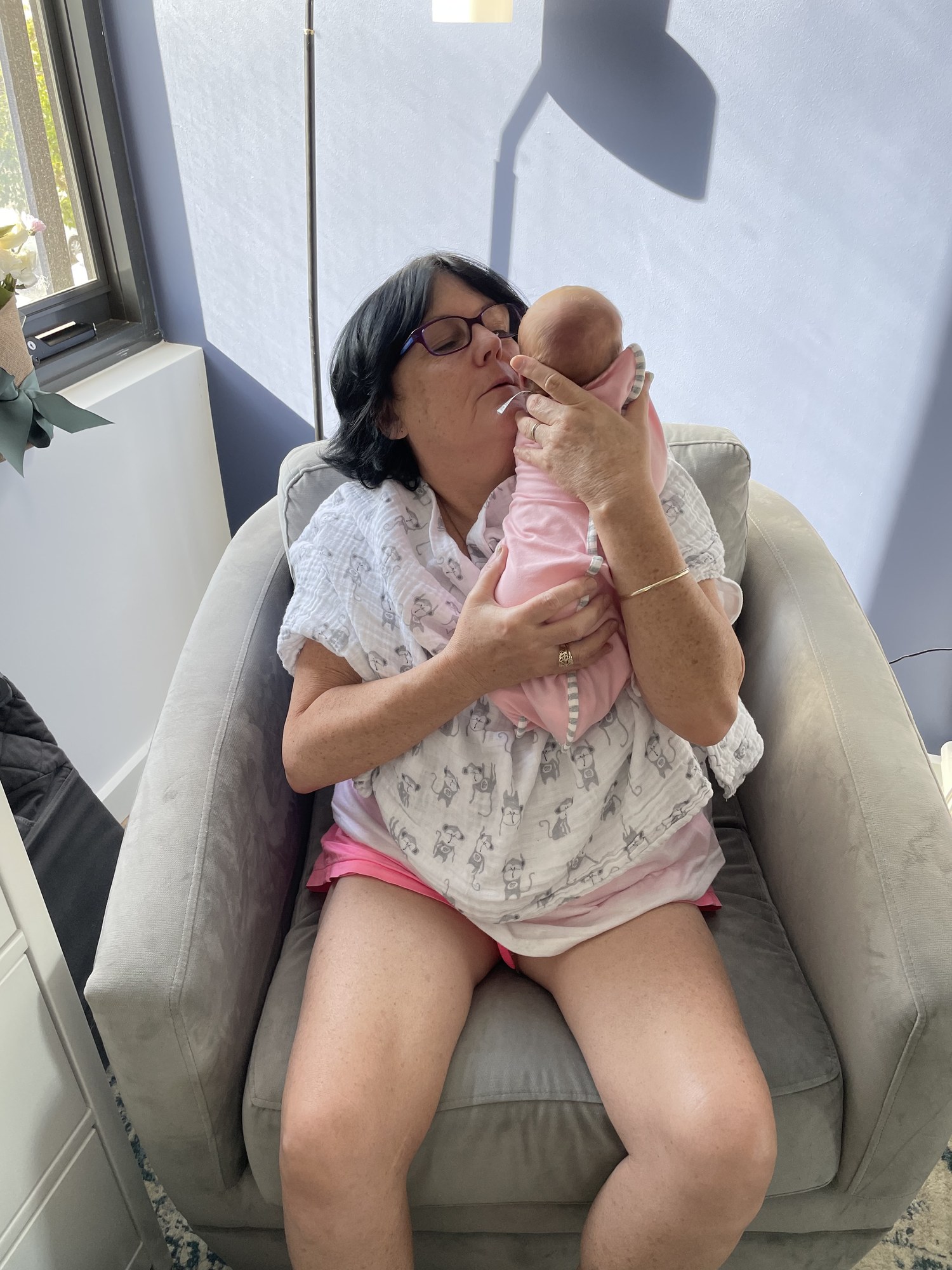 Julie holding a baby while seated on a sofa