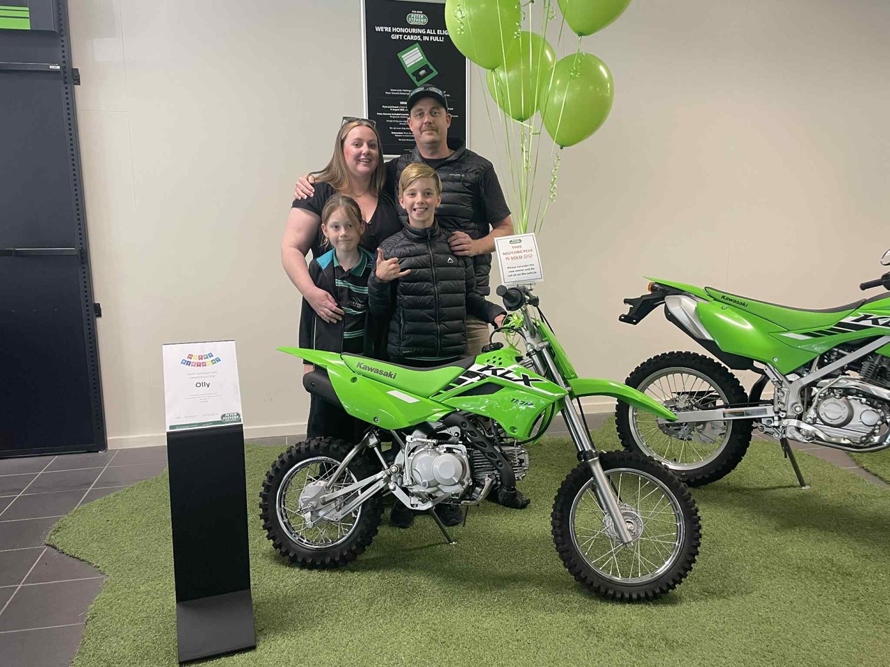 Lawrence and family celebrating beside a new green dirt bike