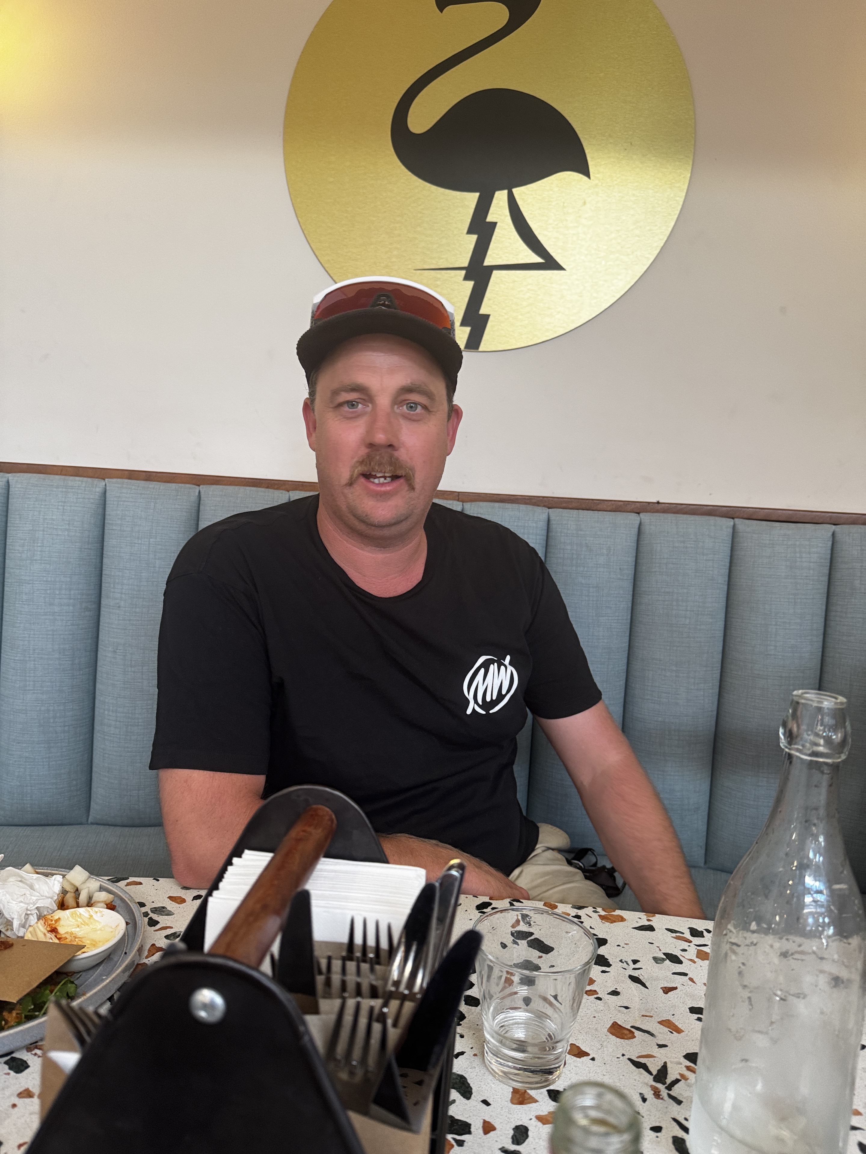Lawrence wearing a cap and sunglasses at a table