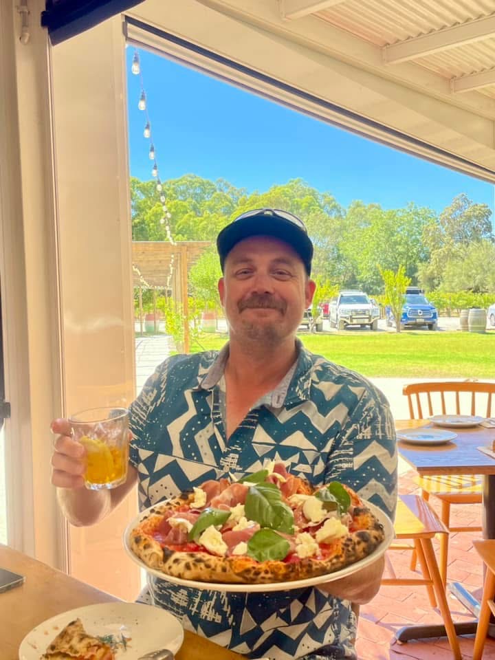 Lawrence holding a pizza at home