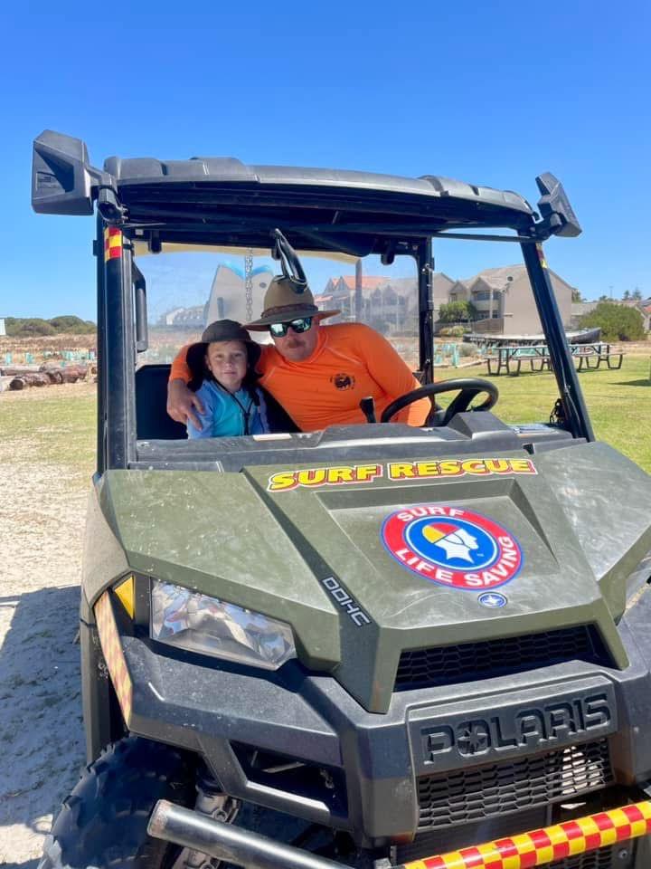 Lawrence with a young family member in a surf rescue vehicle