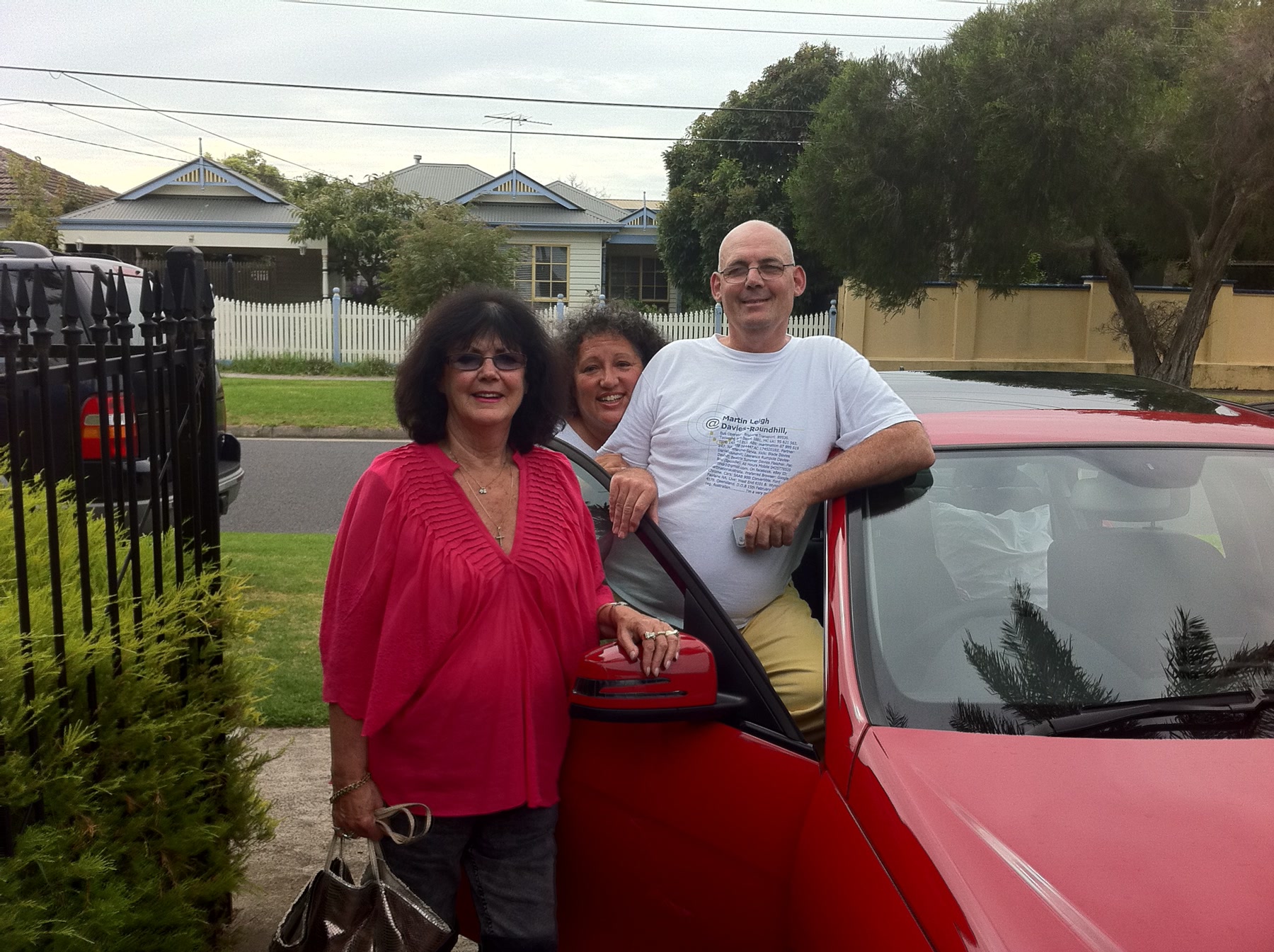 Martin with two unidentified companions beside a red car in Melbourne