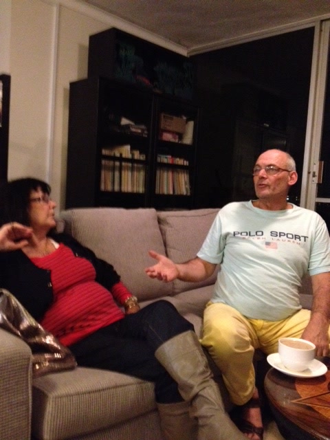 Martin gesturing as he speaks with an unidentified companion on a sofa