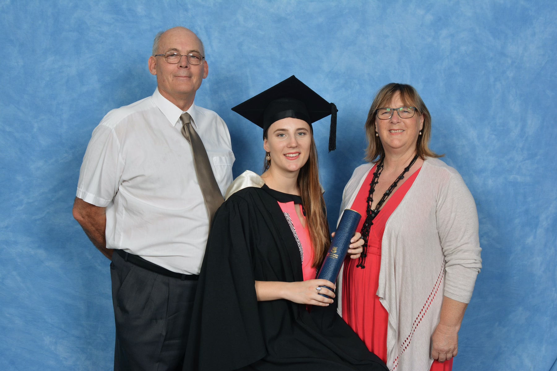 Martin, Beatrix Fletcher in graduation regalia holding a diploma scroll, and Claire Fletcher