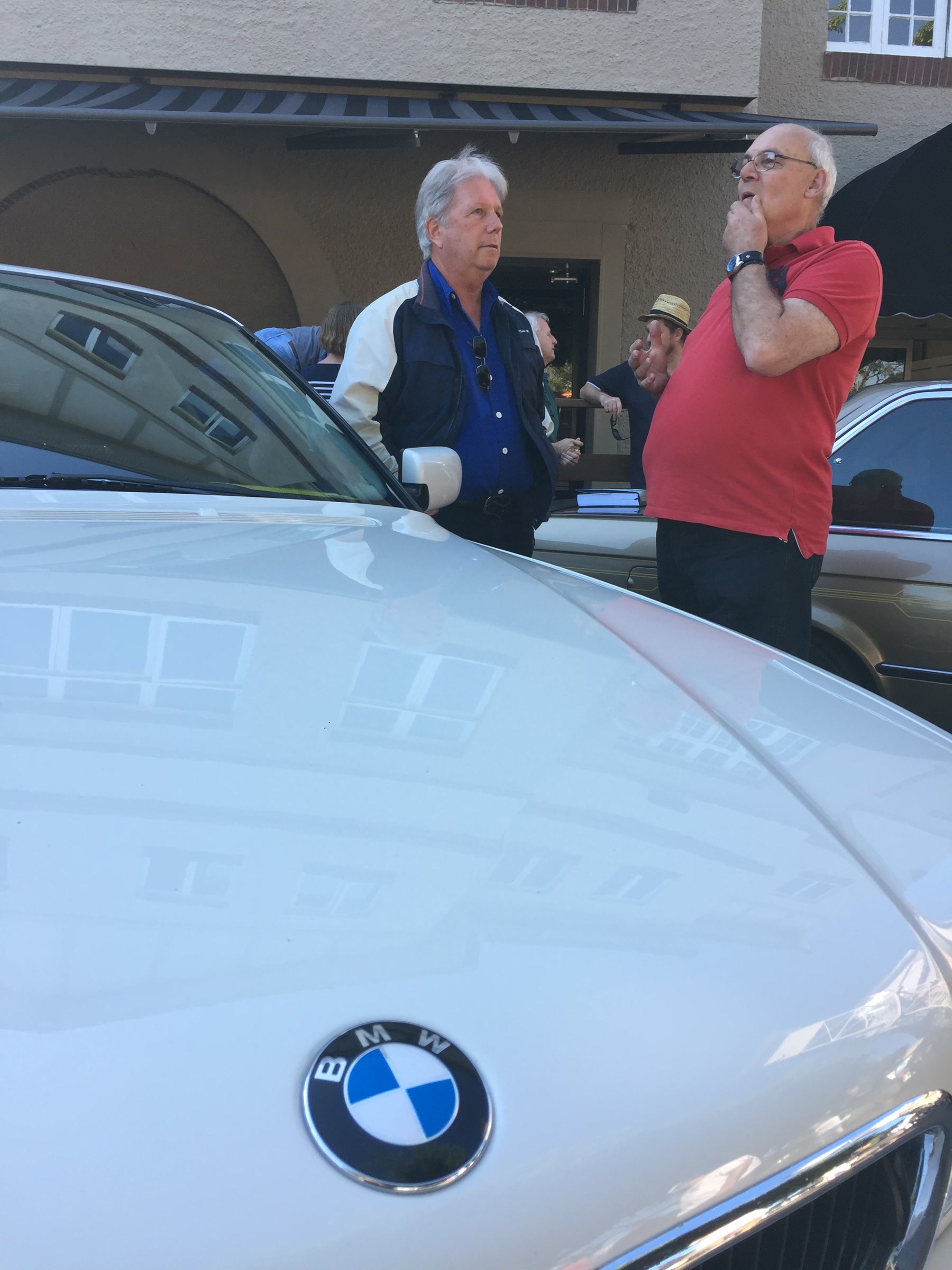 Martin talking with an unidentified man beside two cars in Brisbane