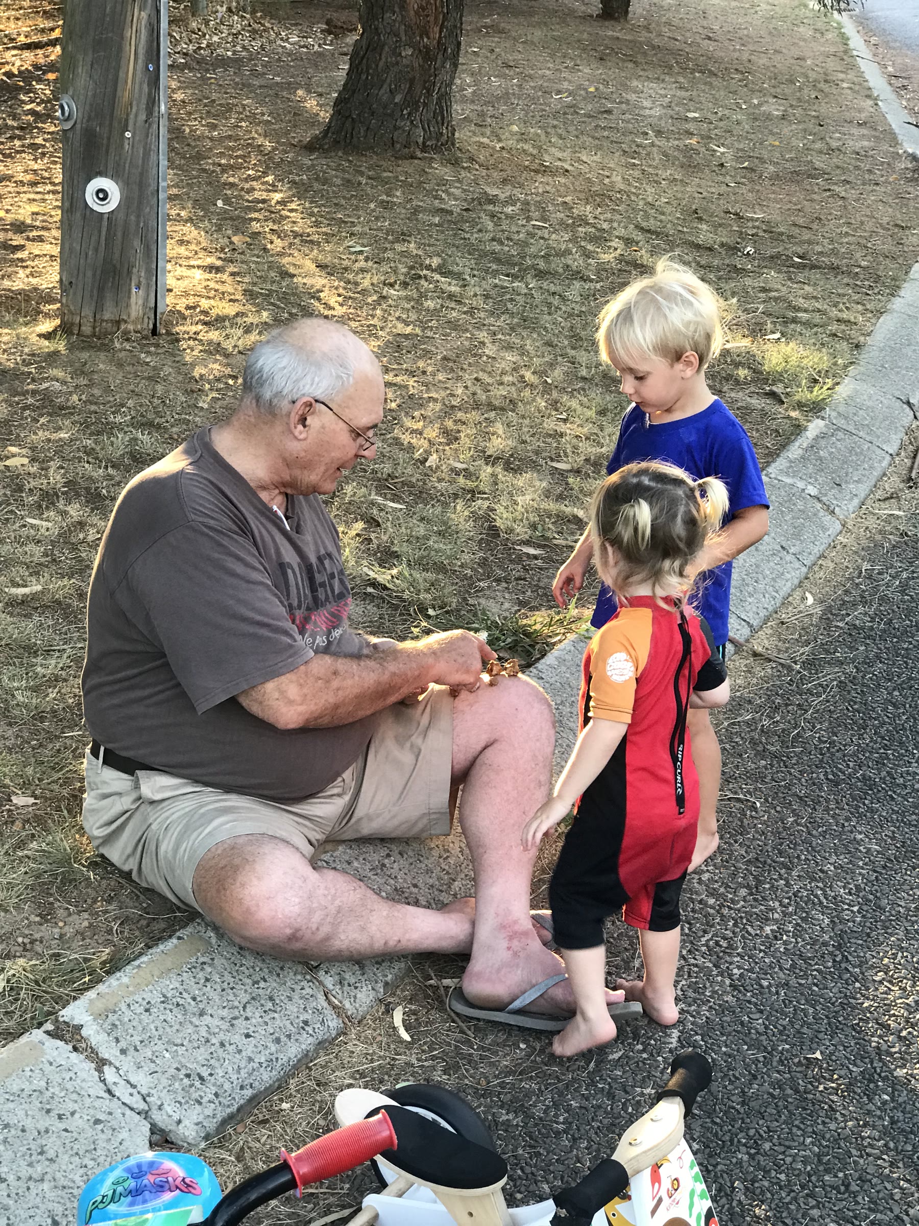 Martin crouching beside two children outdoors in Perth