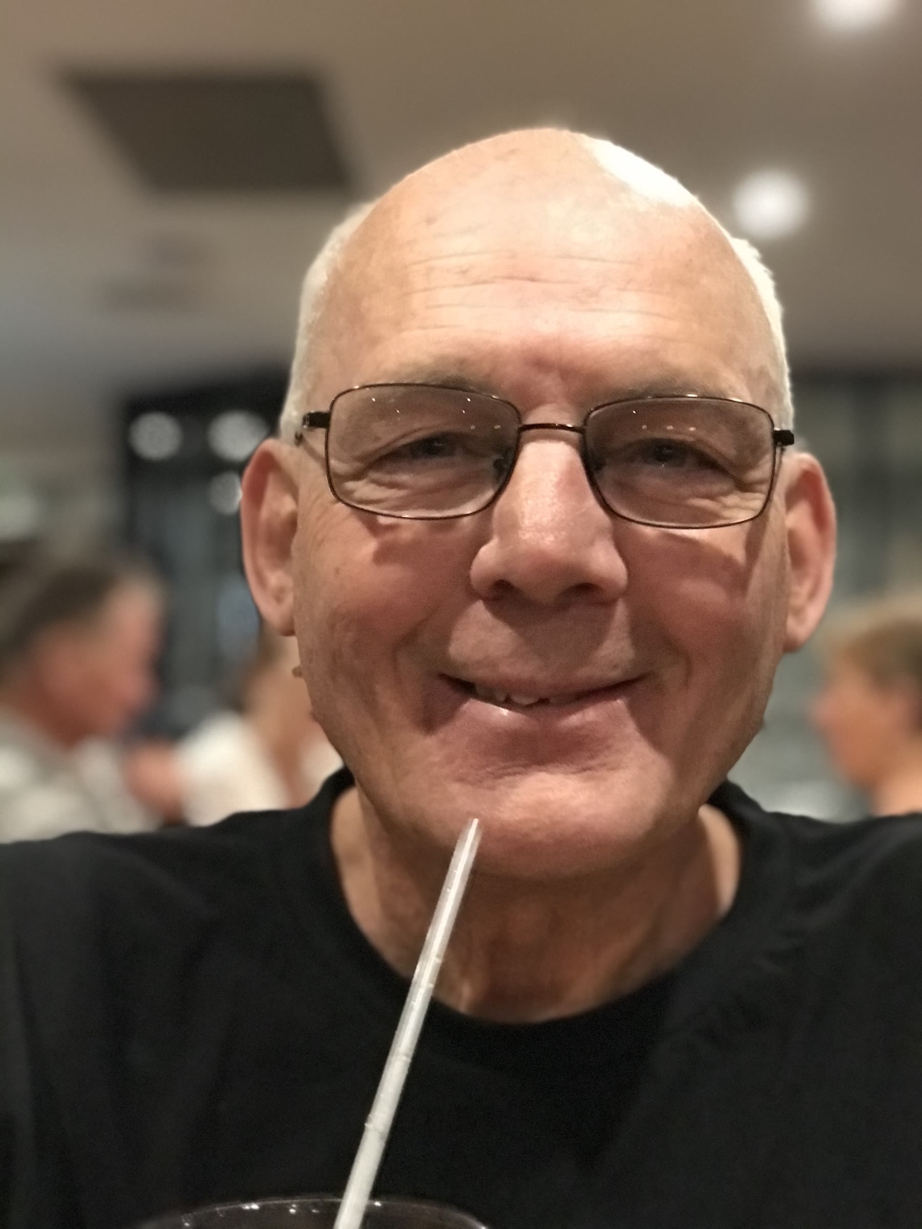 Close portrait of Martin with a drink and blurred diners behind him