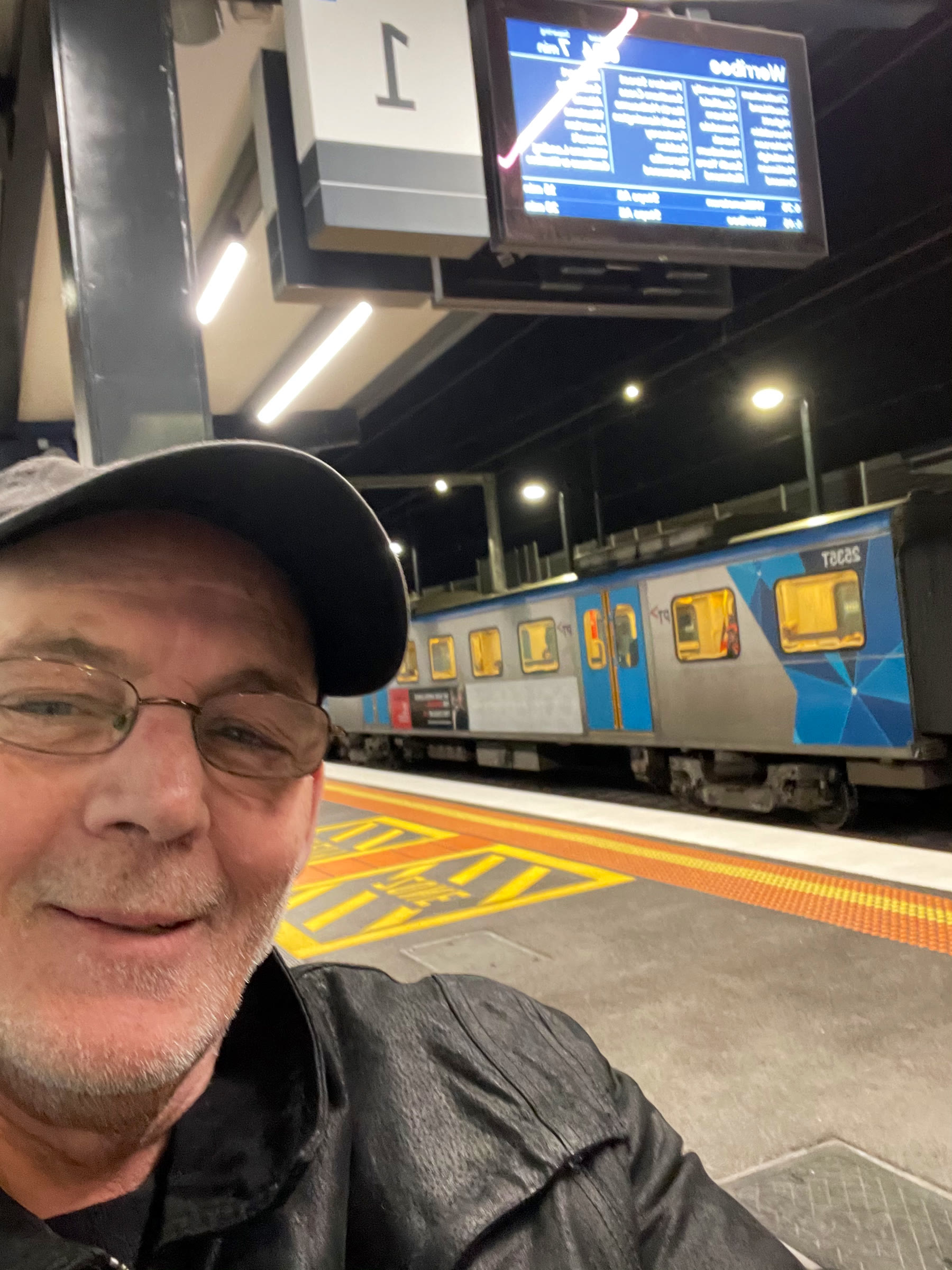 Martin taking a selfie beside a train at a railway platform at night