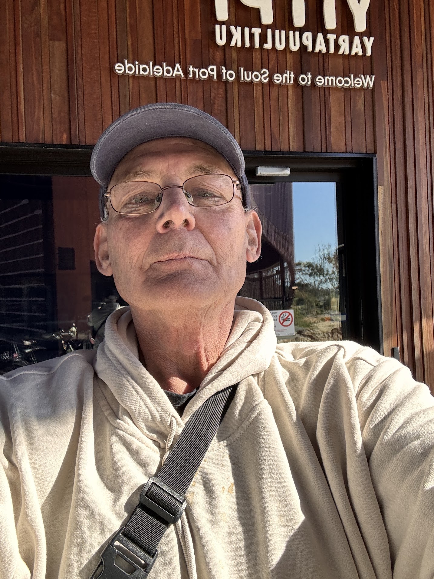 Martin in a selfie in front of a timber-clad entrance with a Port Adelaide sign
