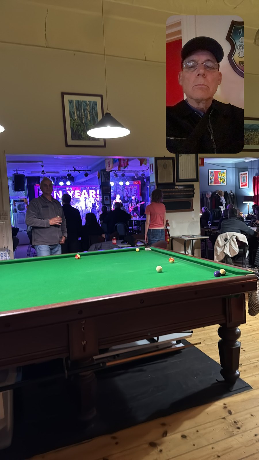 A billiards table and crowd under purple lights, with Martin in an inset portrait