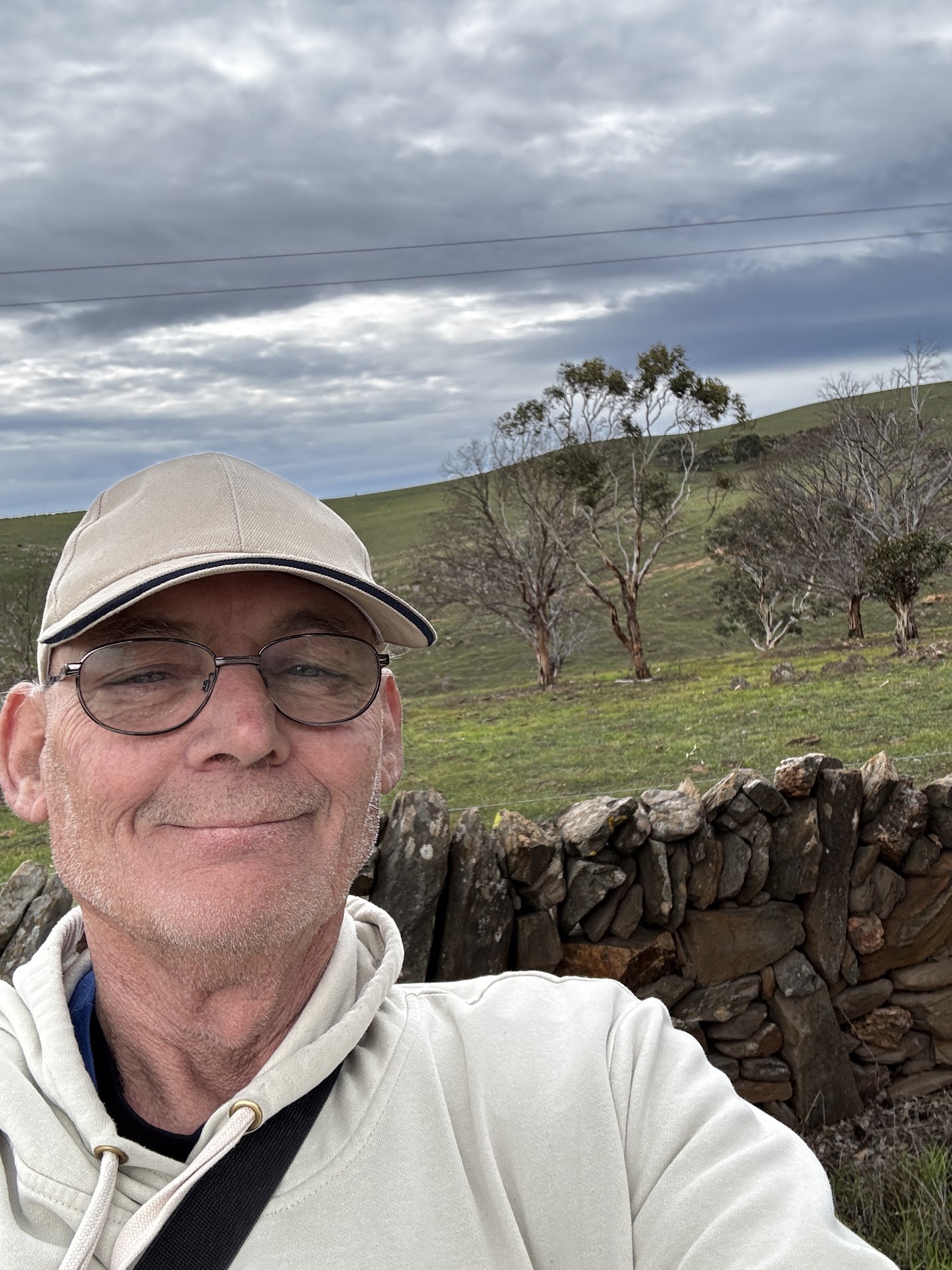 Martin taking a selfie beside a dry-stone wall on a green hillside in Highland Valley